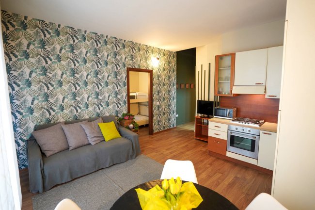 Monolocale con cucina, divano e carta da parati floreale.