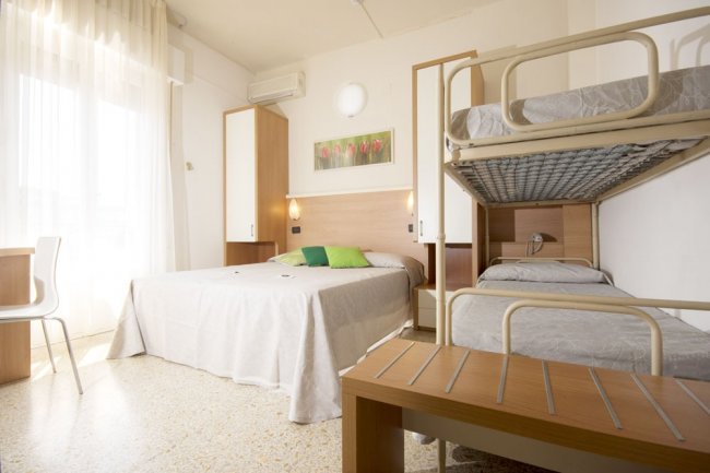 Camera d'hotel con letto matrimoniale e letti a castello.