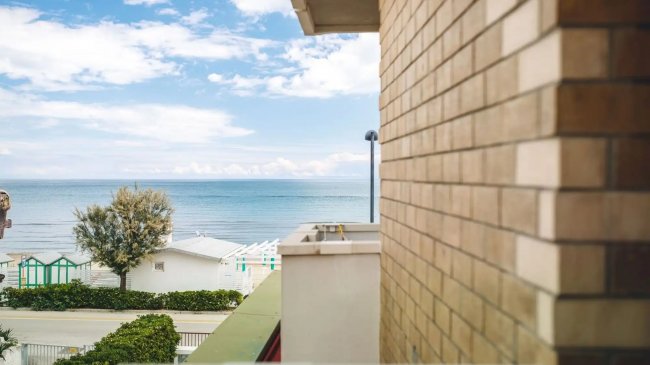 Vista mare da un balcone con muro di mattoni.