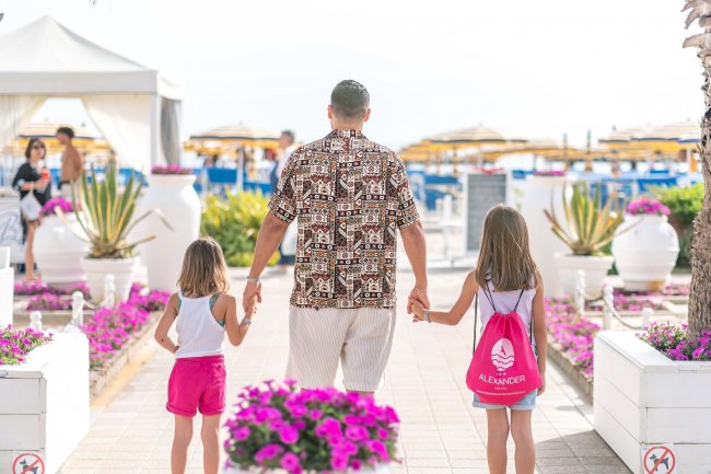Uomo con due bambine cammina verso la spiaggia.