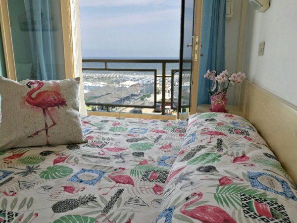 Letto con coperte a tema fenicottero e vista mare.