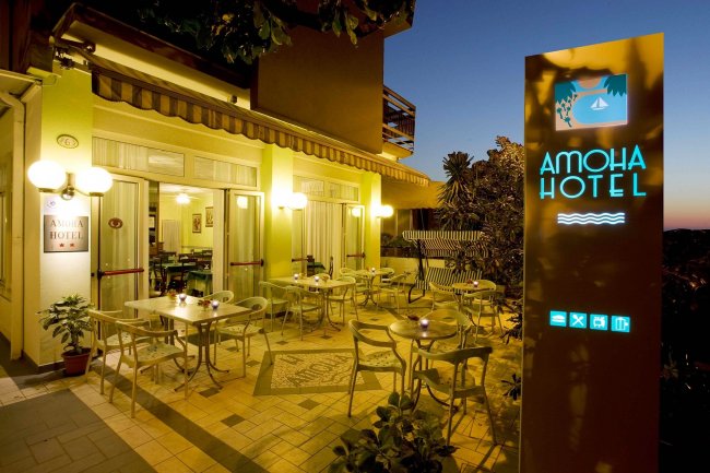 Terrazza esterna dell'hotel con tavoli e sedie illuminate.