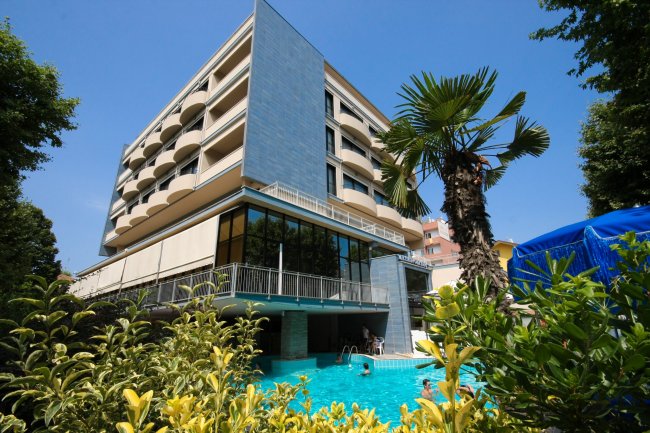 Edificio moderno con piscina e palme.