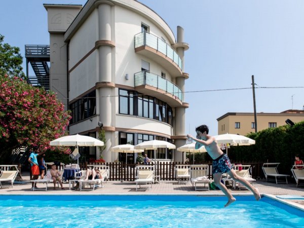Giovane salta in una piscina vicino a un edificio.
