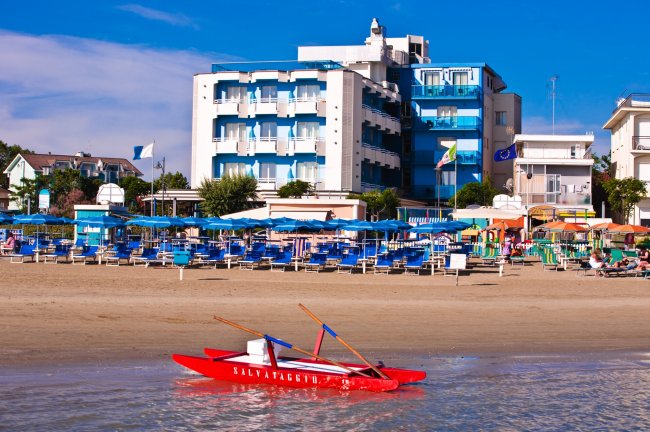 Spiaggia e hotel con cabine e barche.