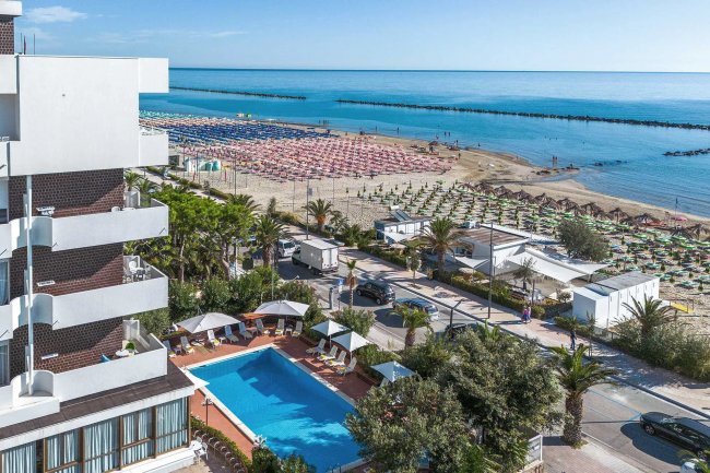 Vista dall'alto di un hotel con piscina e spiaggia adiacente.