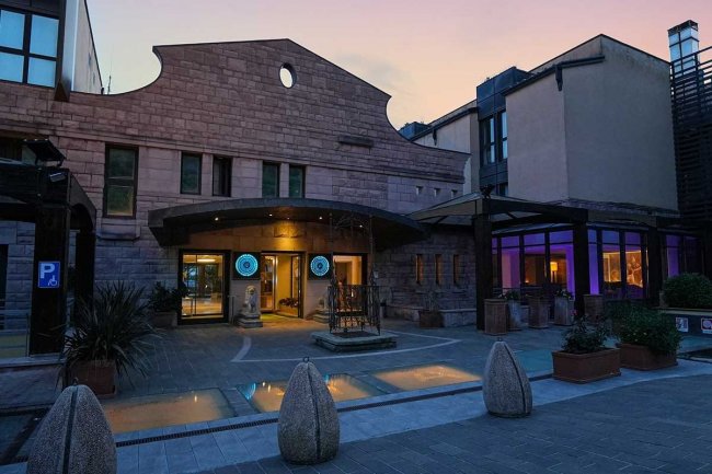 Ingresso di un edificio al tramonto con luci accese.