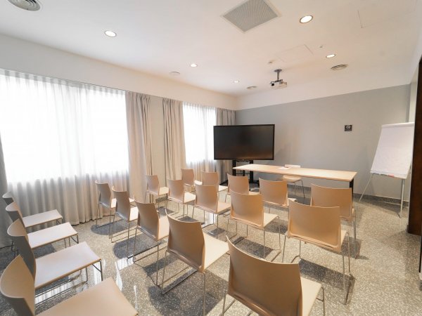 Aula con sedie, tavolo e schermo TV.