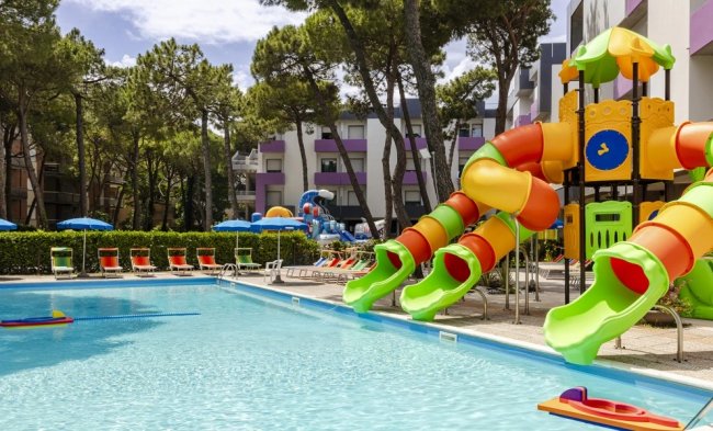Piscina con scivoli colorati e lettini rossi.