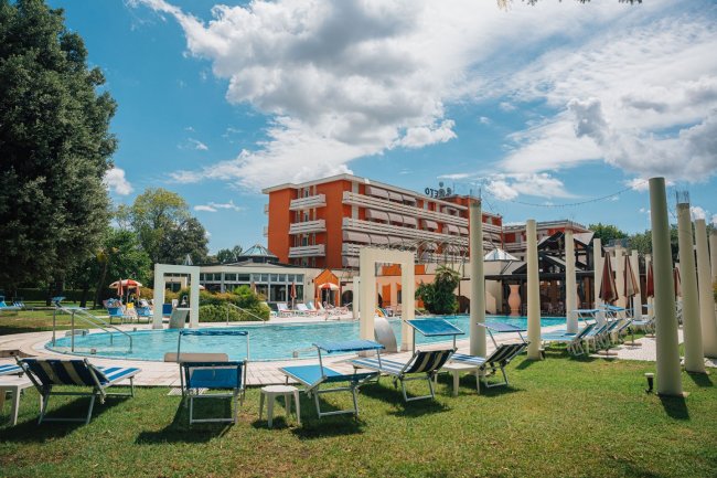 Piscina e lettini davanti a hotel arancione.