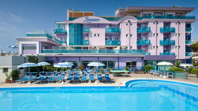 Edificio di un hotel con piscina e lettini.
