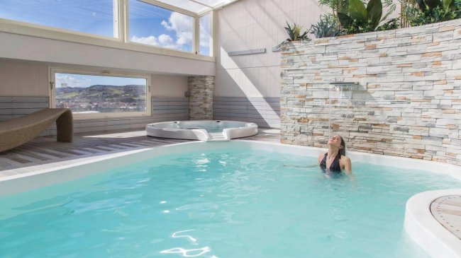 Piscina interna con cascata e idromassaggio.