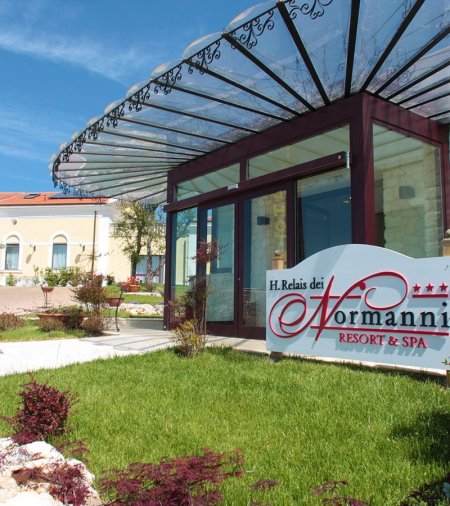Ingresso di un resort con copertura in vetro e insegna visibile.