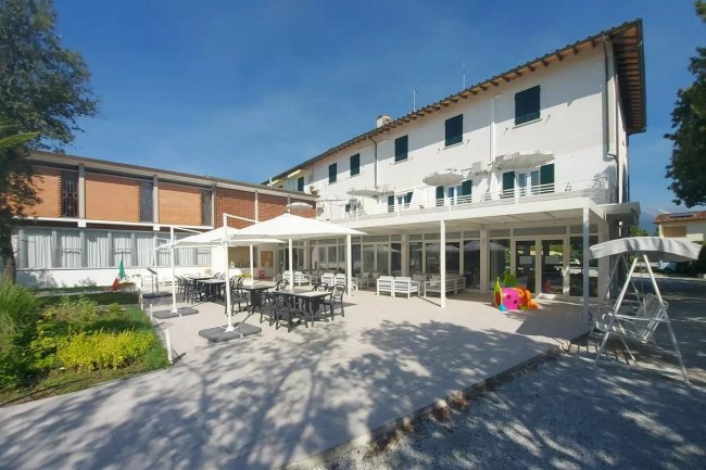 Edificio bianco con terrazza e sedie esterne.