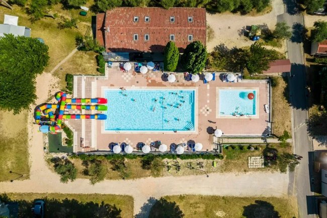 Piscina con persone e scivolo colorato.