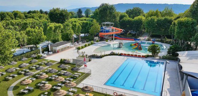 Piscina con prato e ombrelloni, scivolo a spirale.
