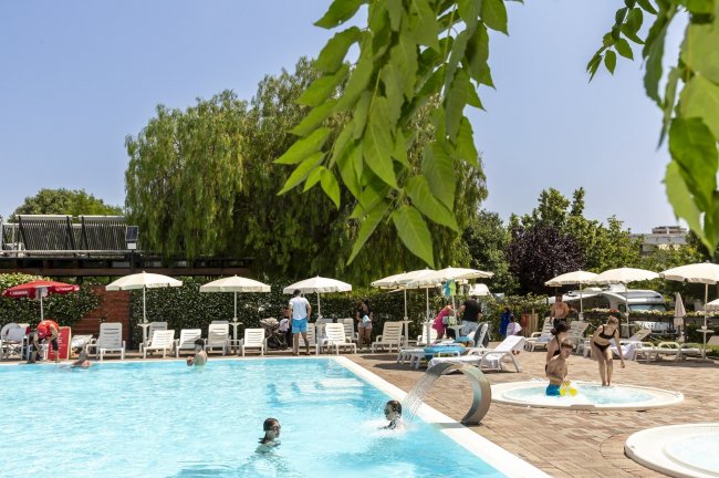 Piscina all'aperto con ombrelloni bianchi.