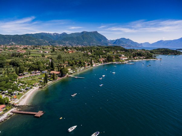 Vista aerea di un lago con barche e montagne.