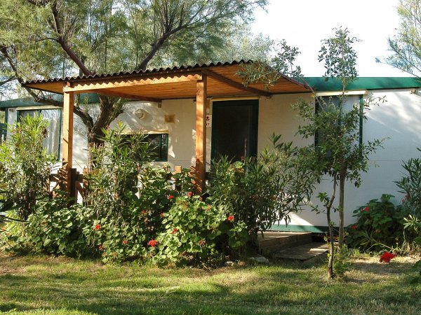 Casetta bianca con veranda e giardino fiorito.
