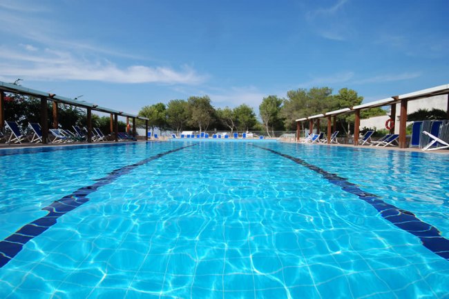 Piscina blu con sedie a sdraio intorno.