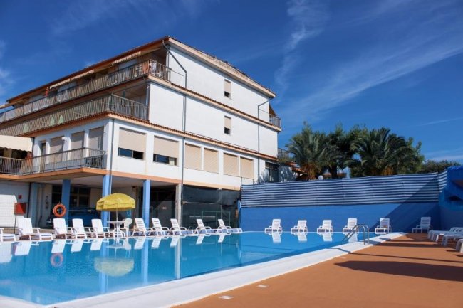 Piscina con sedie a sdraio e edificio sullo sfondo.