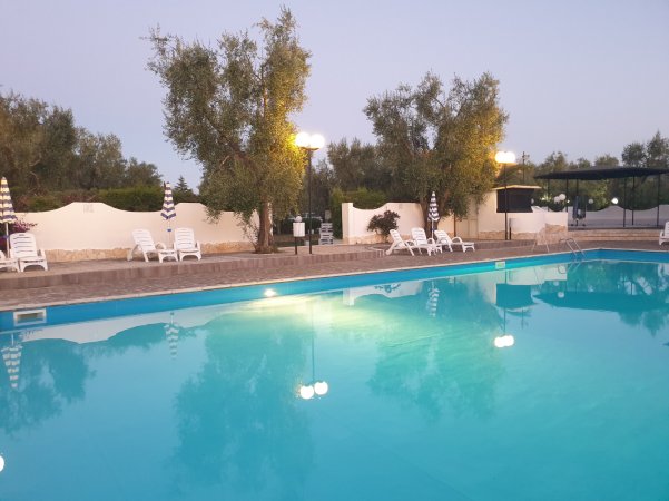 Piscina all'aperto con lettini bianchi.