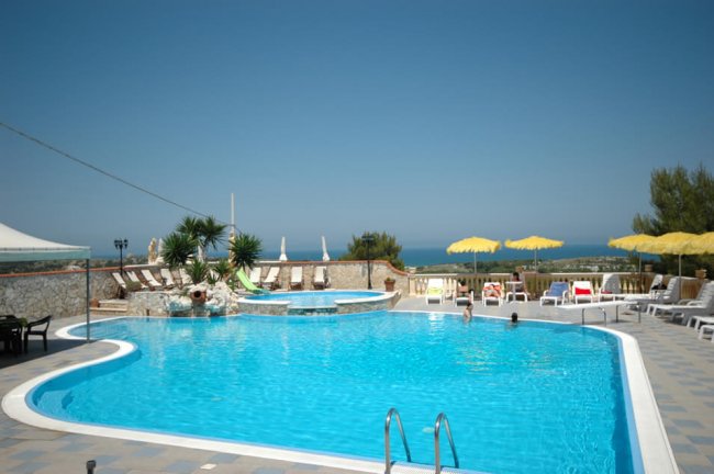 Piscina esterna con lettini e ombrelloni gialli.