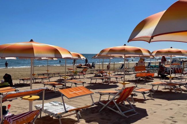 Una spiaggia con ombrelloni e lettini arancioni.