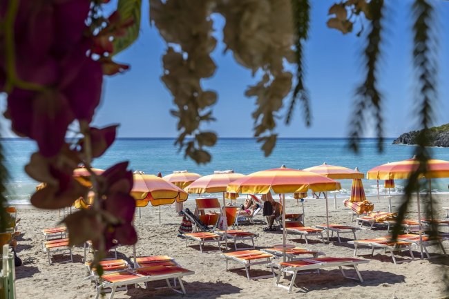 Spiaggia con ombrelloni gialli e arancioni, vista mare.