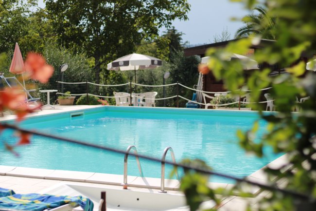 Piscina con ombrelloni e sedie intorno.