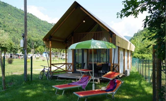 Tenda glamping con terrazzo in un prato verde.