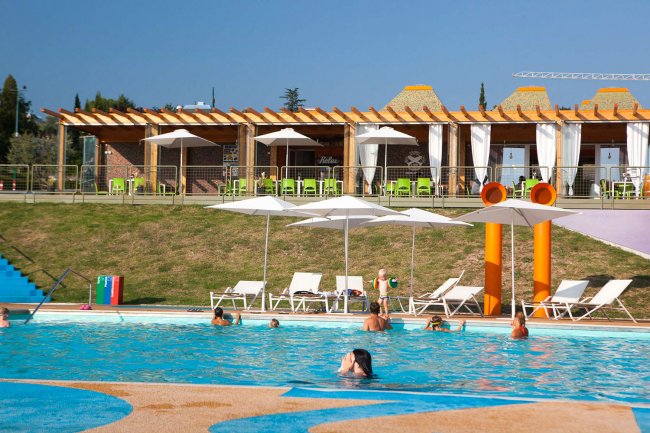 Piscina con lettini e ombrelloni bianchi.