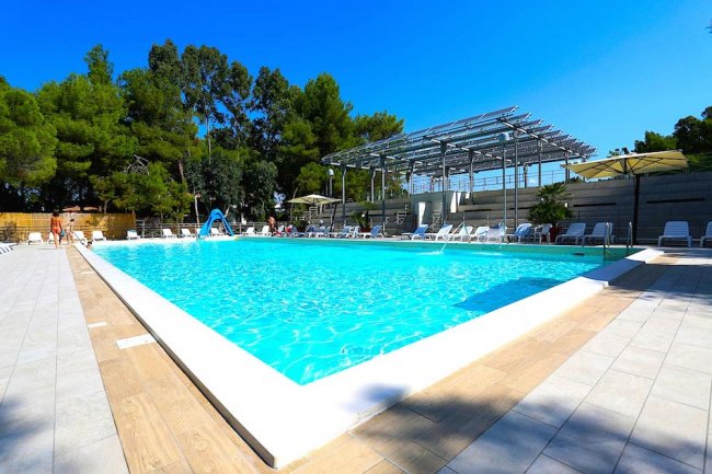 Piscina con sdraio e ombrelloni in un'area soleggiata.