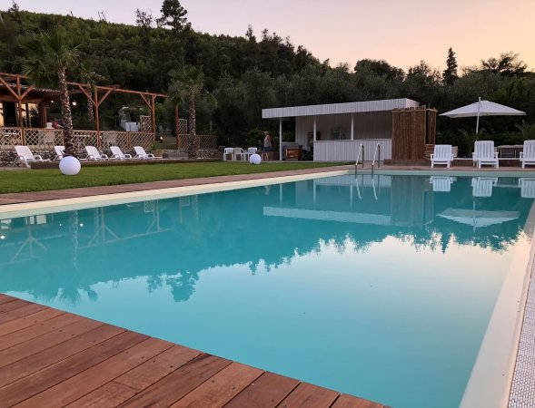 Piscina all'aperto con lettini e ombrelloni.