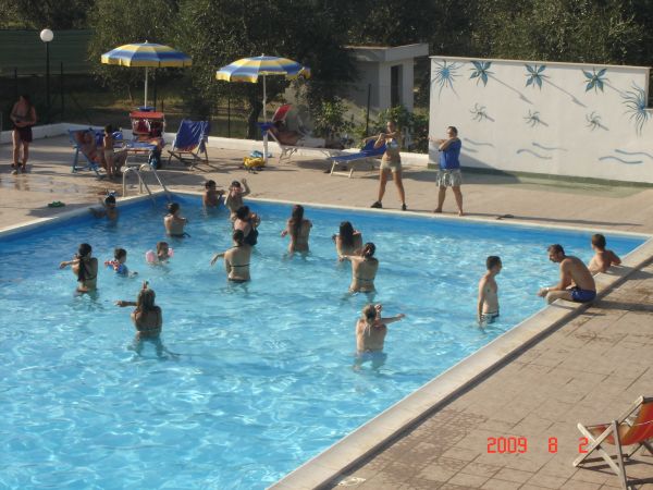 Piscina con persone che nuotano e ombrelloni.