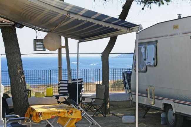Camper con veranda, sedie e tavolo.
