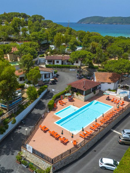 Piscina con lettini arancioni e vista mare.
