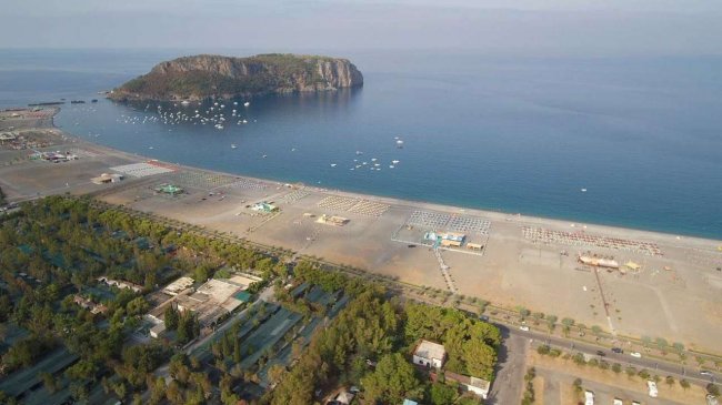 Spiaggia con isola rocciosa sullo sfondo.