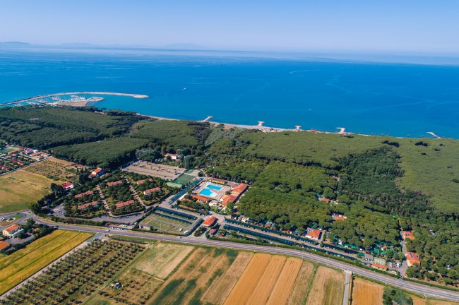 Paesaggio costiero con mare e campi verdi.
