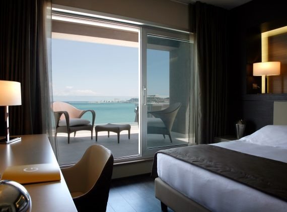 Camera d'hotel elegante con vista sul mare dal balcone.
