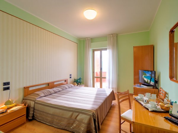 Camera da letto con pareti verdi, letto matrimoniale e TV.