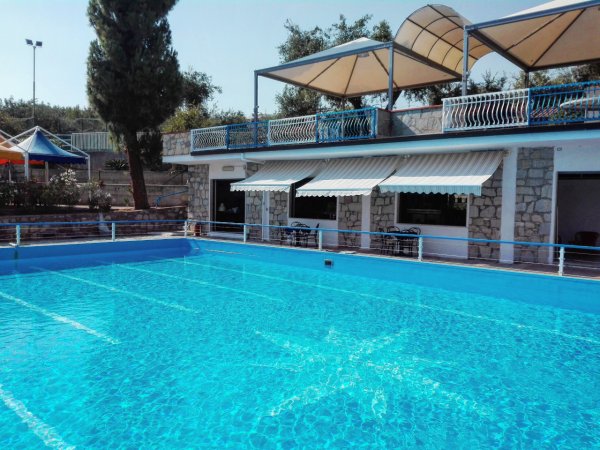 Piscina all'aperto accanto a edificio con tende.