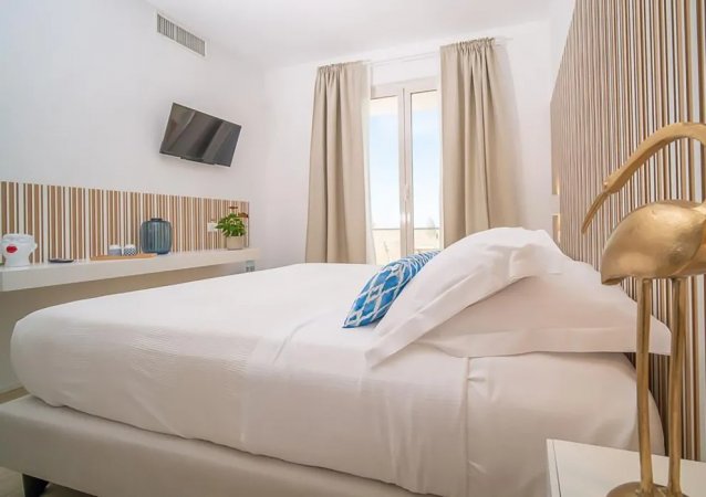 Una moderna camera da letto con arredi chiari e finestra con tende.