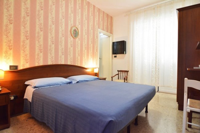 Camera con letto matrimoniale, lampade e sedia.