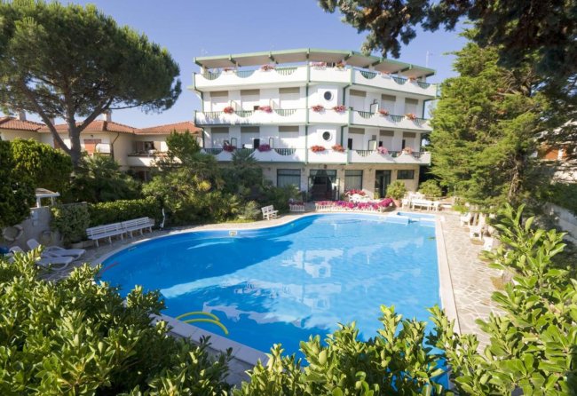 Hotel con piscina circondata da verde.