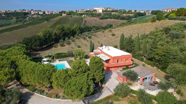 Vista aerea di case con piscina tra colline.