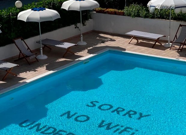 Piscina con lettini e ombrelloni, scritta 