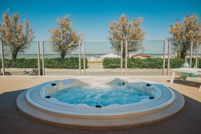 Vasca idromassaggio con vista mare e alberi.