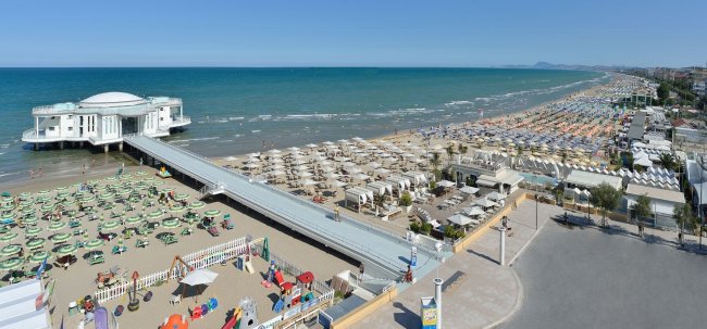 Spiaggia con stabilimento e lungomare affollati.
