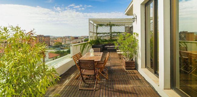 Terrazza con tavolo in legno e piante.